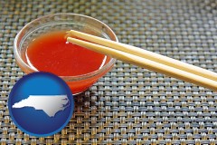 north-carolina map icon and chopsticks and red hot sauce in a Chinese restaurant